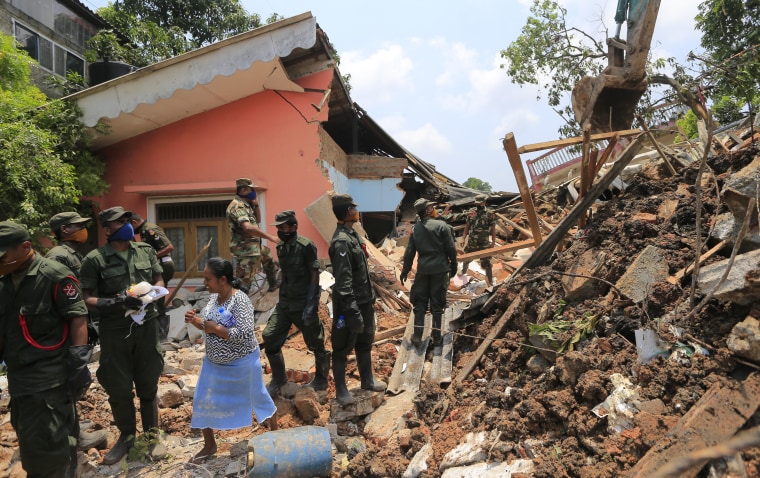 Image: Sri Lankan army rescuers remove debris from a buried house
