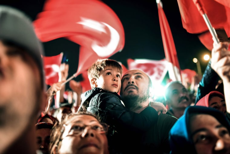 Image: A man holds a child as they wait for President Erdogan t appear for a speech at the AKP headquarters in Istanbul, on April 16.