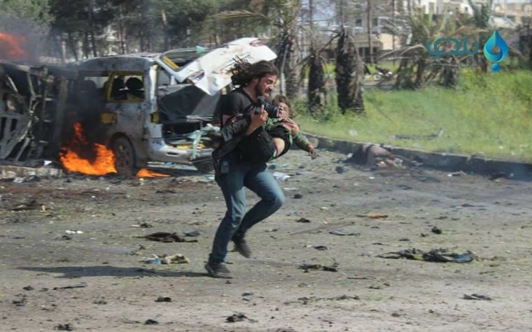 Image: Abd Alkader Habak is photographed carrying a wounded Syrian boy