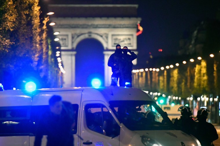 Image: Police look through binoculars  as officers secure the area after a gunman opened fire on the Champs Elysees