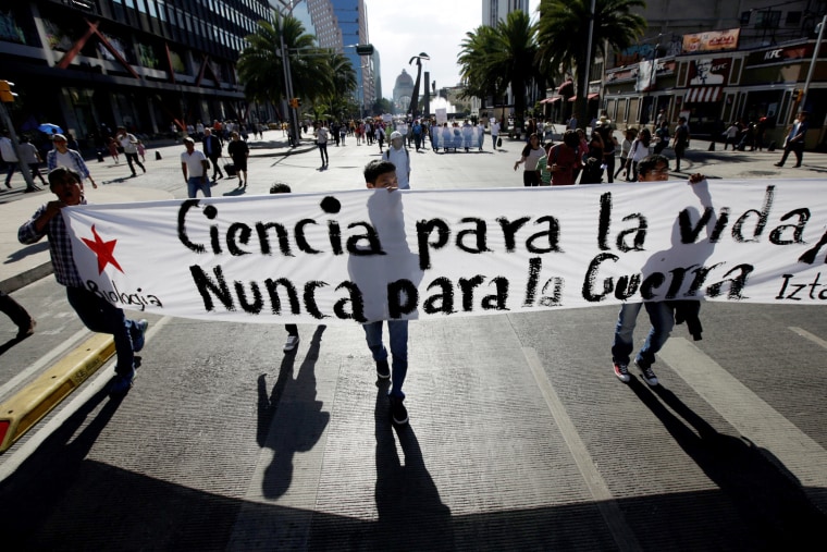 Image: Children hold a banner during the science march in Mexico City, Mexico. The banner reads \"Science for Life, Never for War.\"