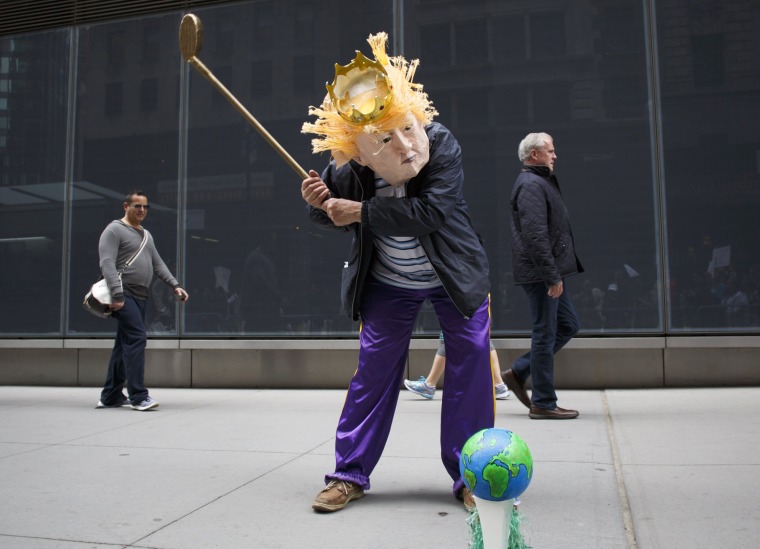 Image: A man in a Donald Trump mask pretends to play golf with the earth during the science march in New York City.