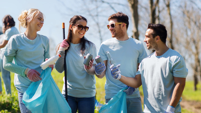 volunteers with garbage bags cleaning park area