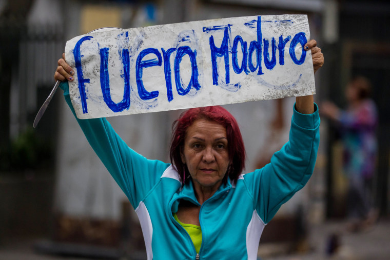 Image: A demonstrator holds a banner that reads, "Maduro Out" during a demonstration in Caracas