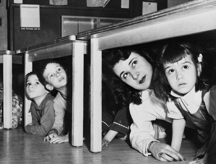 Teacher And Children Crouching Under Table