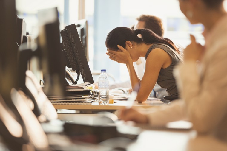 Image: Stressed businesswoman crying with head in hands at office desk