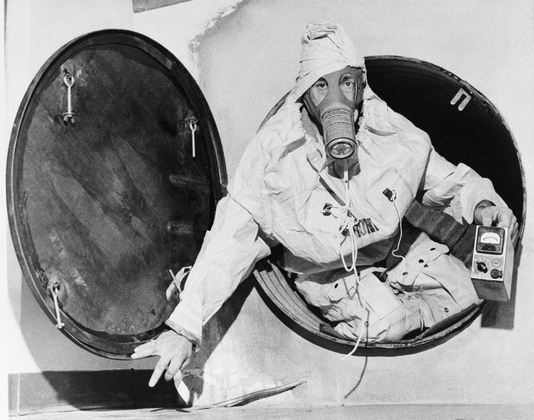 A man wearing protective clothing emerges from a fallout shelter in Medford, Massachusetts in 1961.