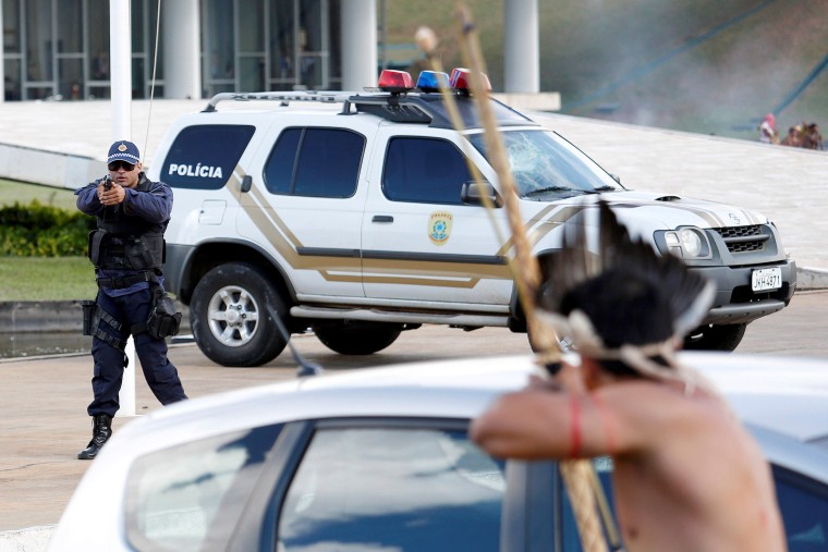 Image: Riot police points his gun at Brazilian Indians during a demonstration against the violation of indigenous people's rights, in Brasilia