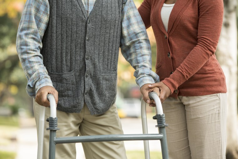 Image: African American woman helping father use walker