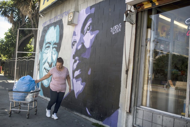 Image: A woman walks past a mural of Cesar Chavez, left, and Martin Luther King Jr., right, in South Central Los Angeles on April 28, 2017, in California.