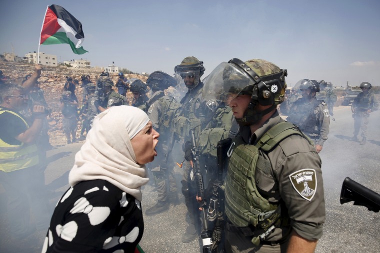 Image: A Palestinian woman argues with an Israeli border policeman during a protest 