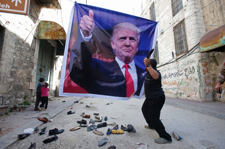 Image: A Palestinian demonstrator throws an old shoe at a poster of US President Donald Trump