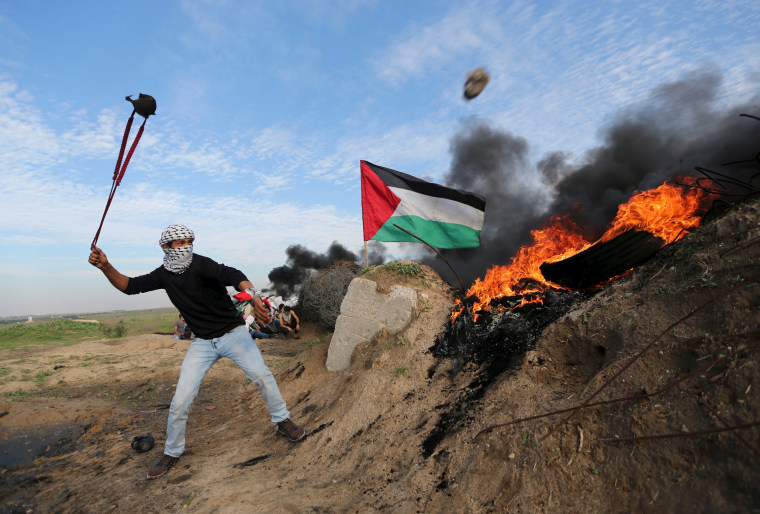 Image: Palestinian protester uses a sling to hurl stones towards Israeli troops during clashes near the border between Israel and Central Gaza Strip