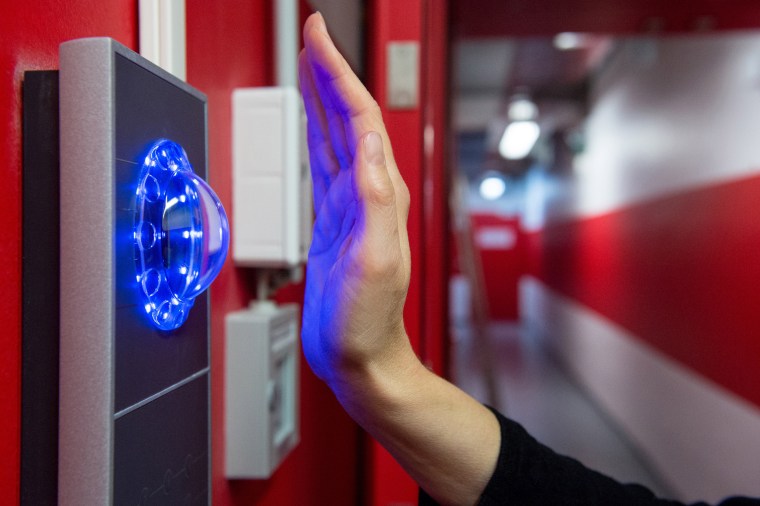 An employee holds a hand up to a blood vessel scanner at the entrance to an internet company in Berlin.