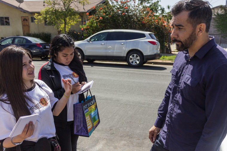 Boyle Heights Beat reporters Samantha Olmos and Jennifer Lopez speak to a participant at a neighborhood walk informing residents of effects of contamination by Exide Technologies.