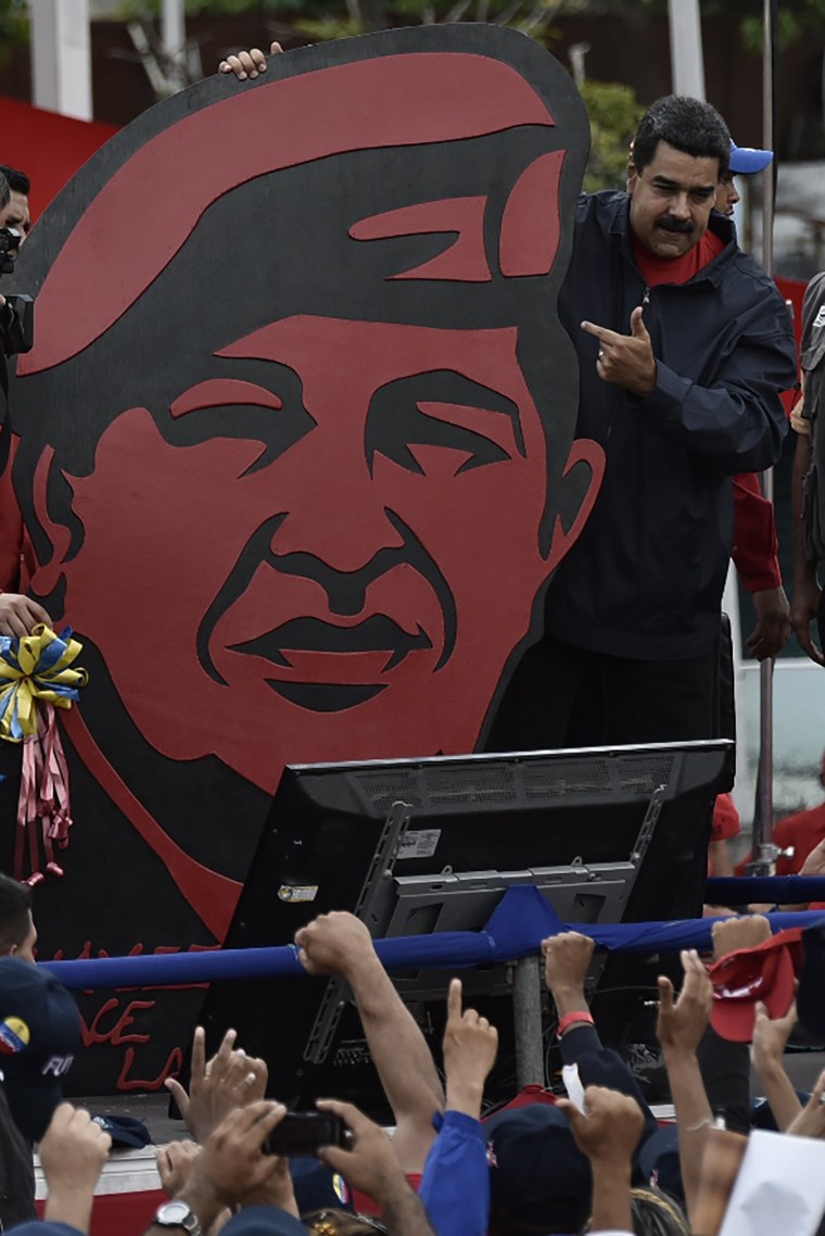 Image: President Nicolas Maduro stands next to a placard depicting late leader Hugo Chavez