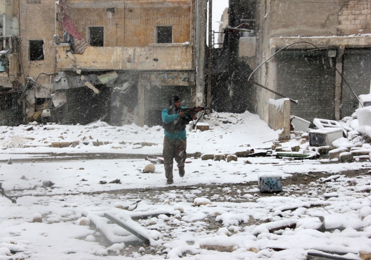 Image: A rebel fighter aims his weapon as he stands amidst snow during clashes with Syrian pro-government forces