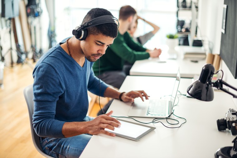 Image: A man wears headphones in an office