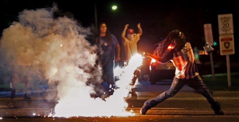 Image: Edward Crawford returns a tear gas canister fired by police