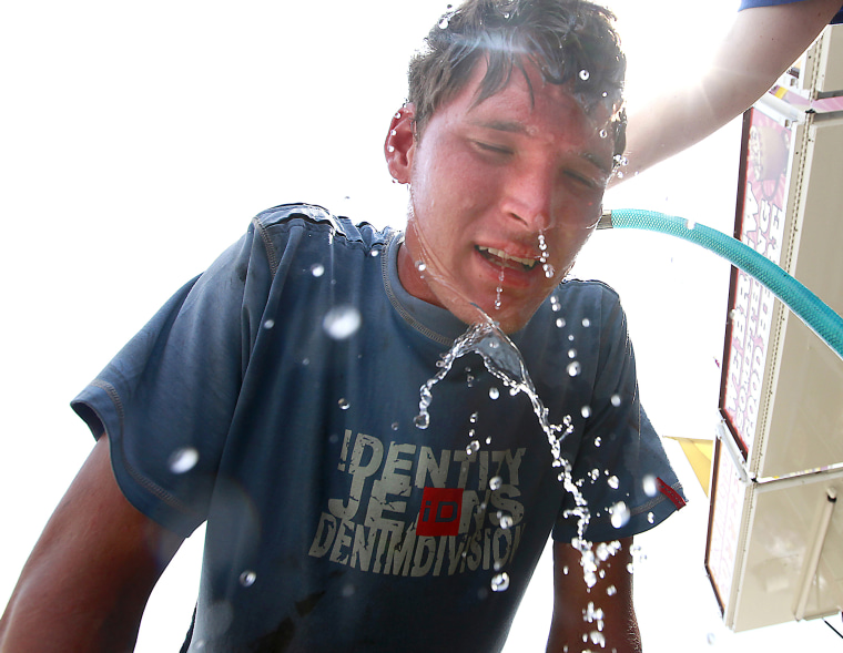 Image: Leon Buys is doused in water while taking a break from midway set-up chores at the Dane County Fair in Madison, Wisconsin on July 19, 2011.