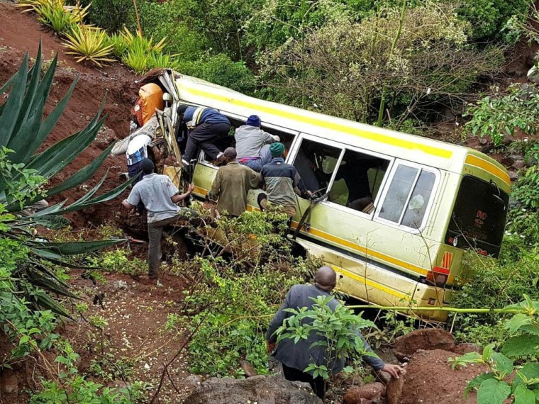 Image: Residents attempt to rescue survivors at the scene of an accident that killed schoolchildren, teachers and a minibus driver along the Arusha-Karatu highway in Tanzania's northern region of Arusha