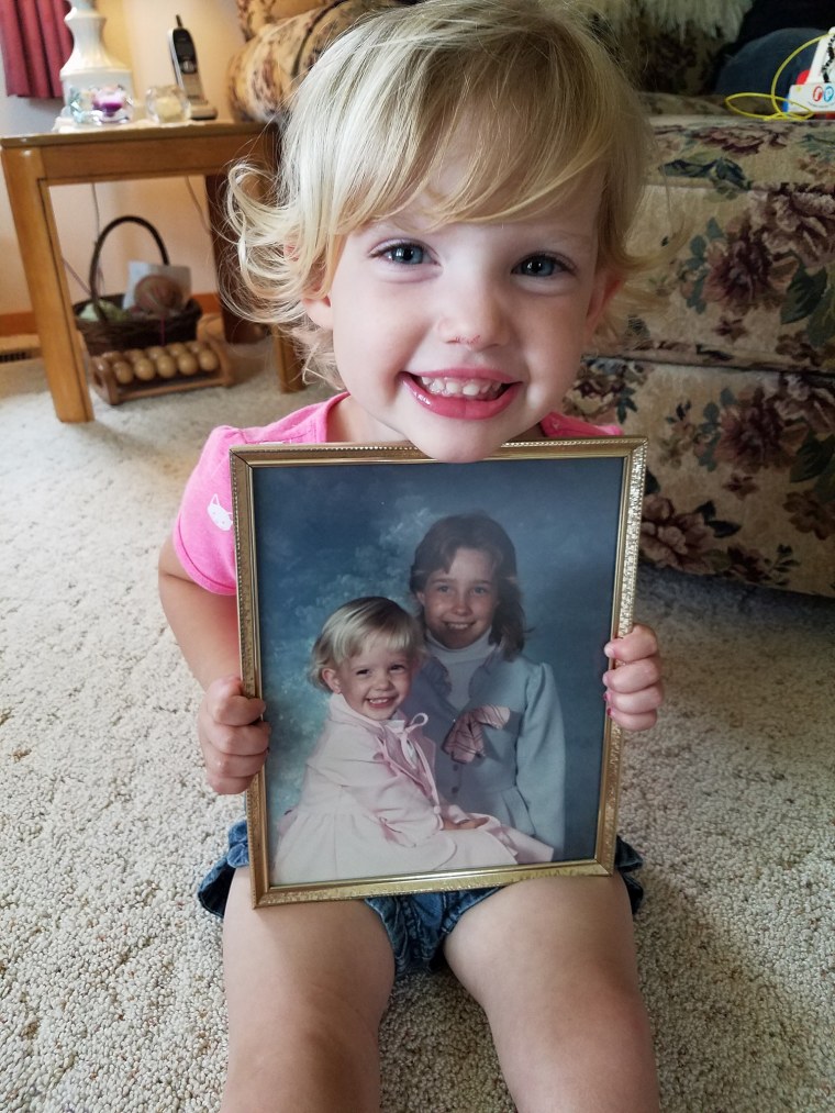 Kelli Soesbe's daughter, Arianna, 3, holding a photo of her mom at age 4. 

