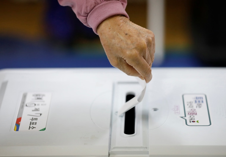 Image: A woman casts her vote at a polling station in Seoul