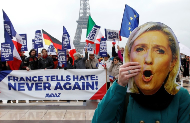 Image: A protester holds a Marine Le Pen mask near banner reading "France Tells Hate: Never Again"