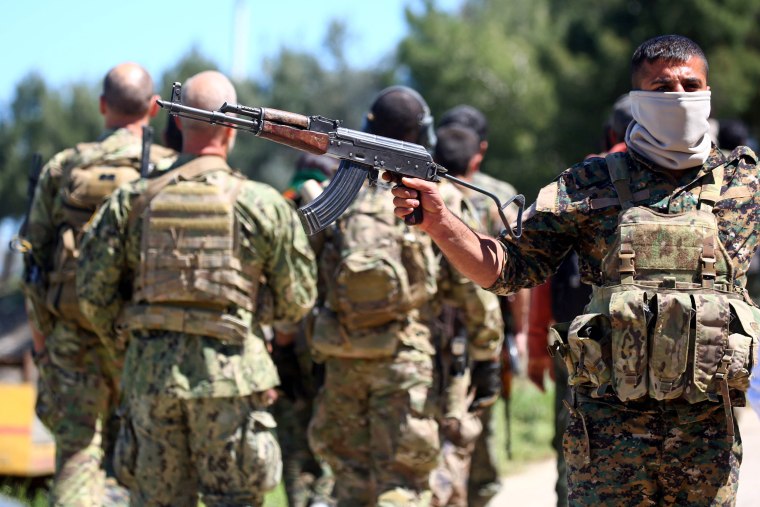 Image: Fighters from the Kurdish People's Protection Units (YPG) stand guard at the site of Turkish airstrikes