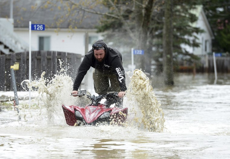 Image: A homeowner drives his ATV down the flooded Chemin Belisle