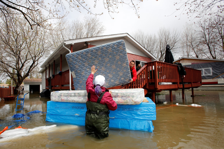Image: Jean-Francois Perrault and Julie Theriault move mattresses from a home in a flooded residential area in Gatineau