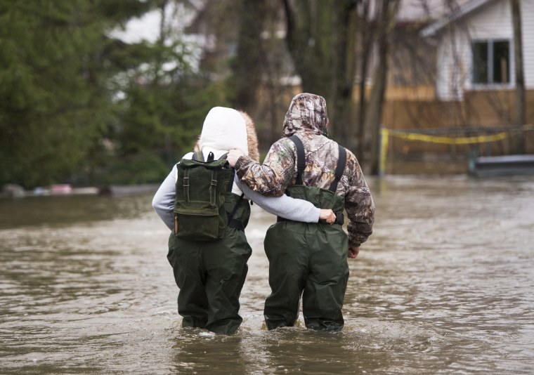 Image: A couple walks through the flooded streets in the Ile-Mercier district of Ile-Bizard, Quebec