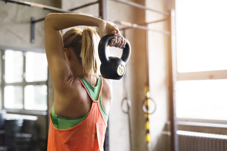 Image: Woman in gym working her arms with kettle bell