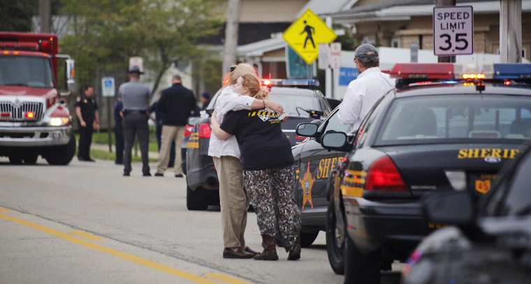 Image: People hug as emergency personnel arrive to the scene of a shooting outside Pine Kirk nursing home