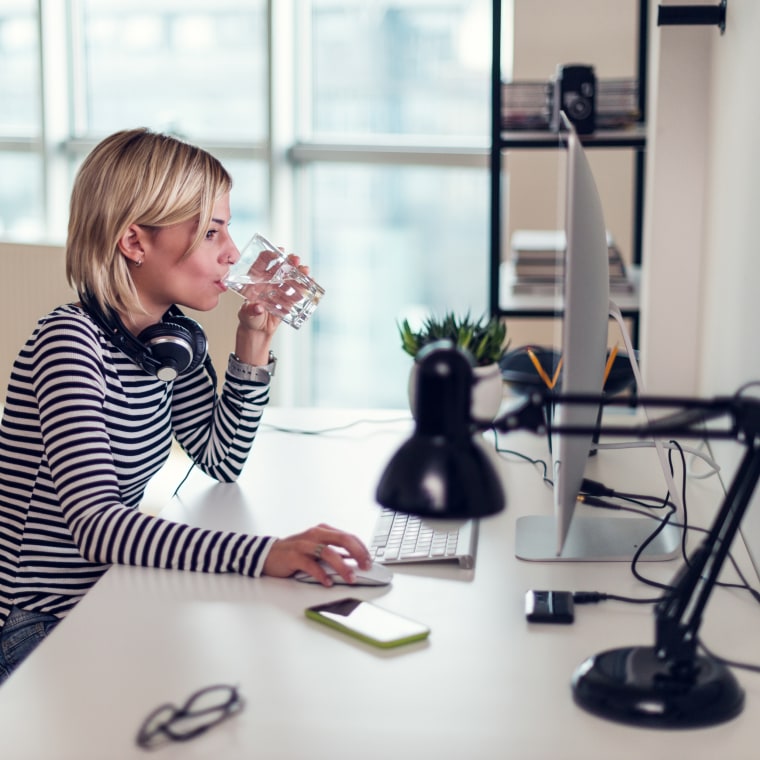 Image: Woman at computer having glass of water