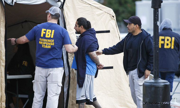 Image: A man is taken into custody by FBI agents