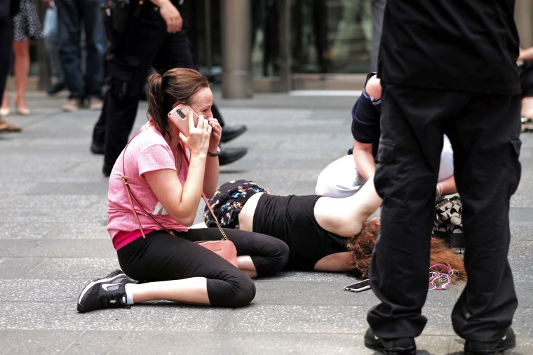 Image: A woman makes a phone call as others attend to an injured person after a car plunged into them in Times Squar