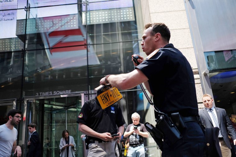 Image: A Police officer collects the license plate of a car after it plunged into pedestrians in Times Square