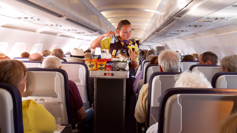 A flight attendant member of the cabin crew serving food on a Monarch Airlines airplane from Madeira to Gatwick airport, UK