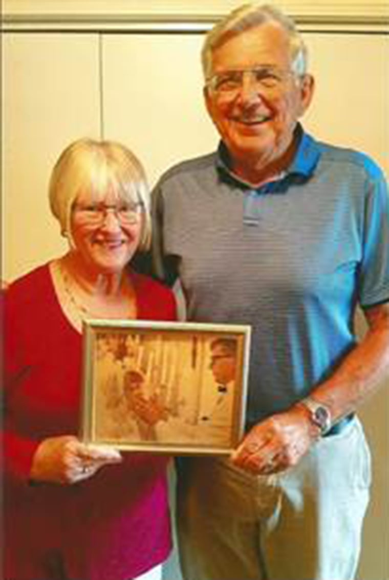 Mike and Carol Anderson holding a beloved photo of them on their wedding day, when his look deep into her eyes told her he loved her.