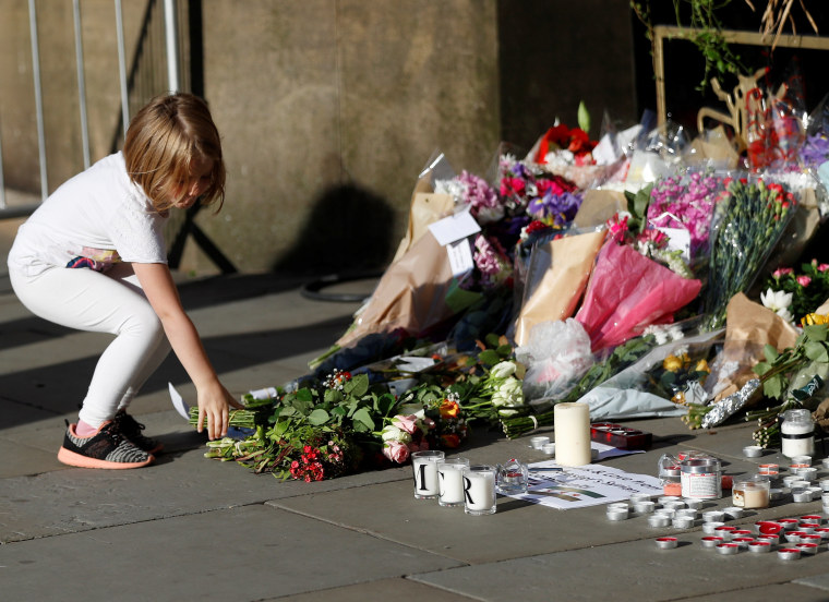 Image: A girl leaves flowers for the victims of an attack on concert goers at Manchester Arena, in central Manchester