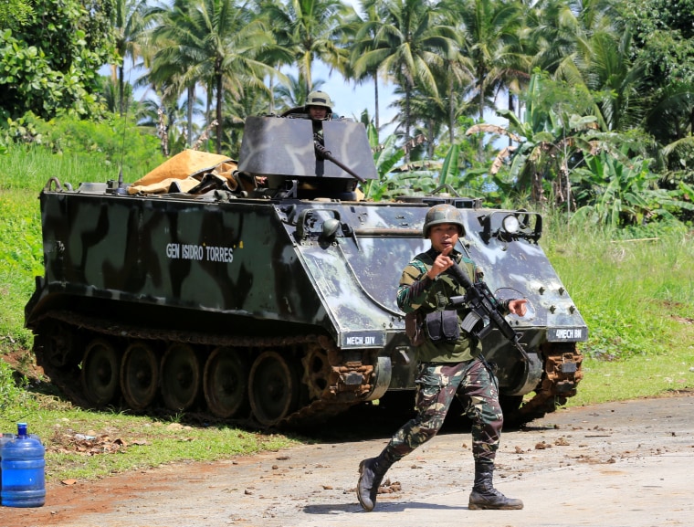 Image: A government troop gestures as he passes an armored personnel carrier posted along a main highway of Pantar town, after residents started to evacuate their hometown of Marawi city