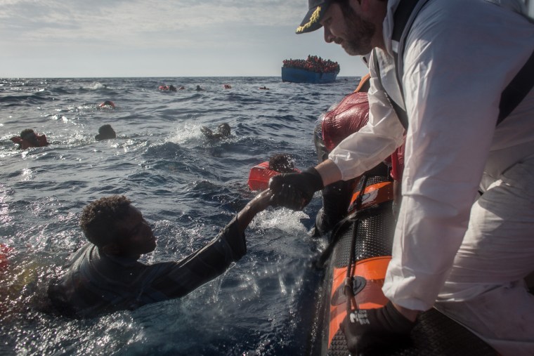 Image: Crew on the Migrant Offshore Aid Station (MOAS) vessel 'Phoenix' help a man bound for Italy, Wednesday.