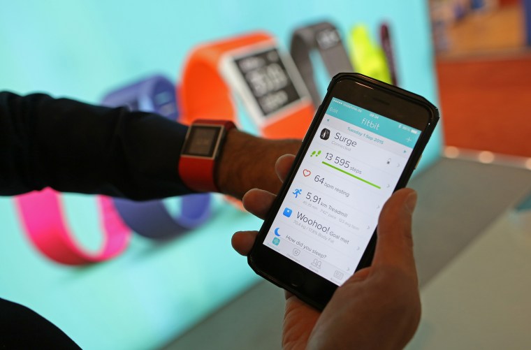 Image: An employee checks his health and fitness data from a connected Fitbit Inc. Surge watch on a smartphone