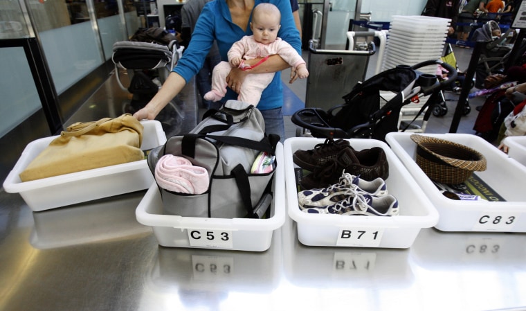 Image: A Passenger Holding her baby prepares to go through a security checkpoint at Los Angeles International Airport