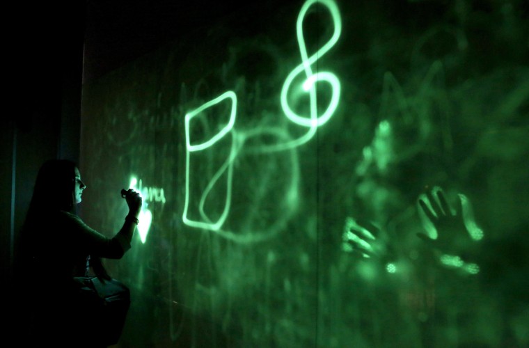 Image: A visitor uses a UV flashlight to paint on an installation