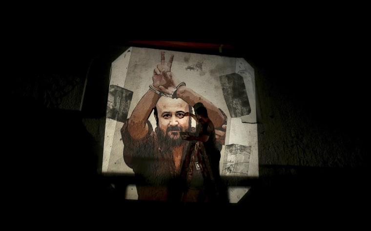 Image: A Palestinian paints an image of Marwan Barghouti on a wall on the streets of Gaza City.