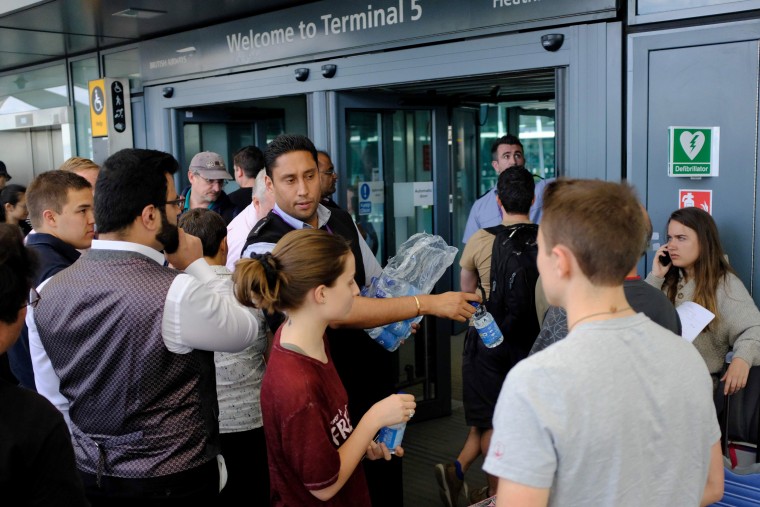 Image: An employee distributes water to stranded travelers outside the entrances of Heathrow Airport Terminal 5 after British Airways flights where canceled at Heathrow Airport in west London on May 27, 2017.