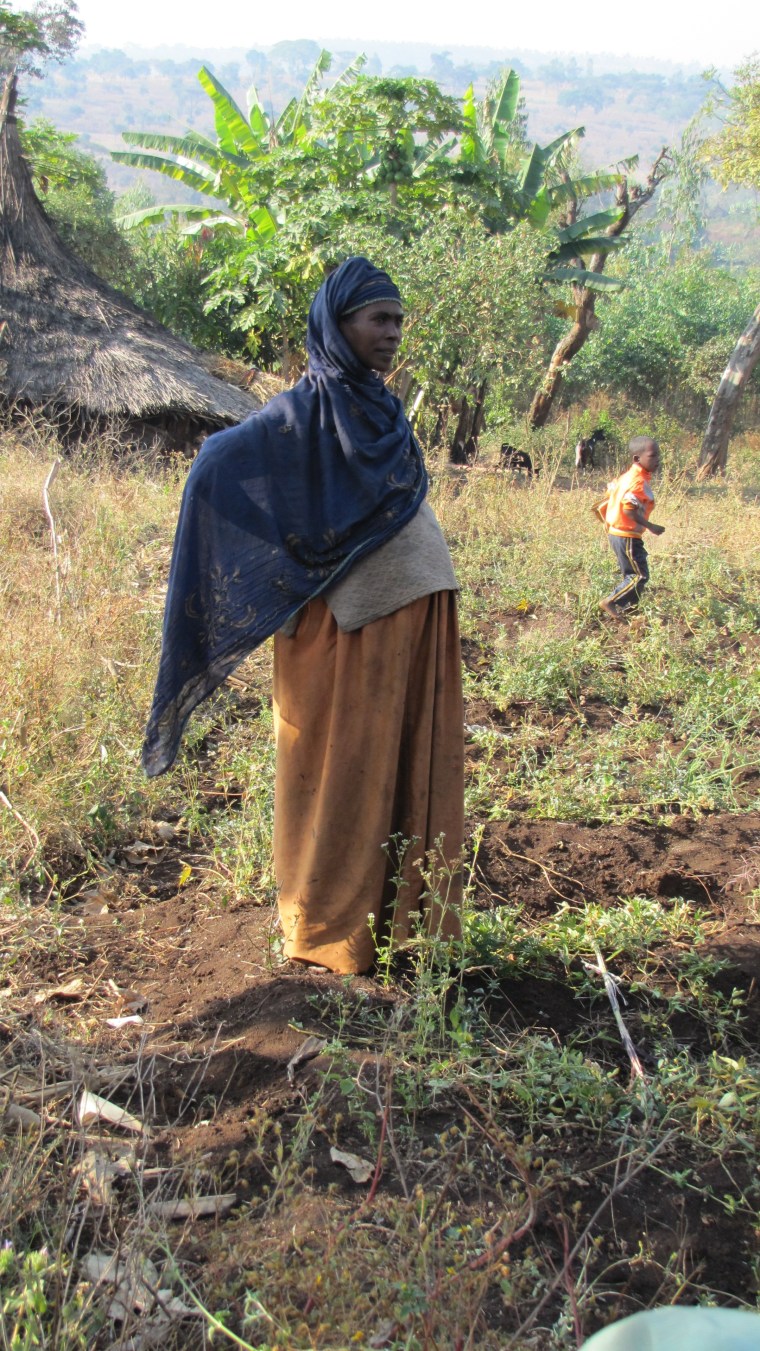 A pregnant woman stands at a refugee camp.