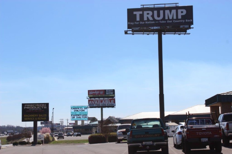 Image: A pro-Trump sign stands above others near carpet and flooring outlets and factories in Whitfield County